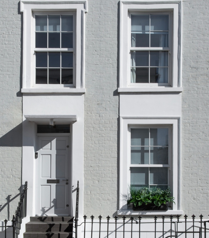 Façade de maison rénovée avec peinture blanche et encadrements de fenêtres